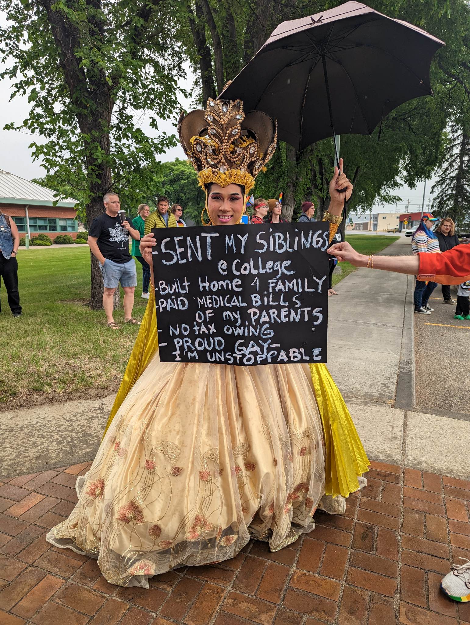 Francheska Dynamites holding a sign that reads: Sent my siblings to college, Build a home 4 family, Paid medical bills of my parents, No tax owing, Proud Gay, I'm Unstoppable.